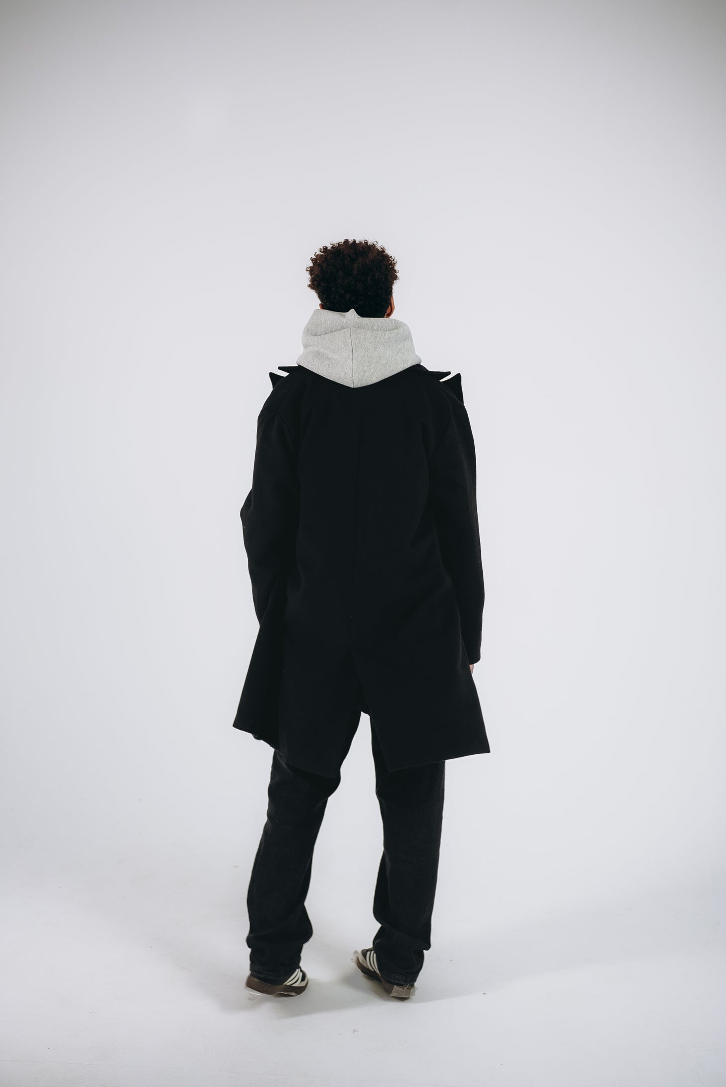 a model has a Back shoot for black coat with hoodie