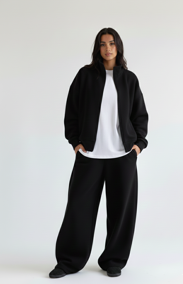 Person wearing Riot Leveret Club black zip-upsweater, white boxy T- shirt, and black balloon effect sweatpants on a white background